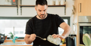 Man pouring liquid from jar in kitchen